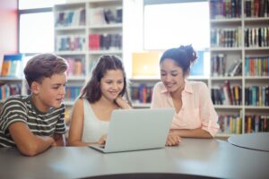 Three children looking at a laptop in a library